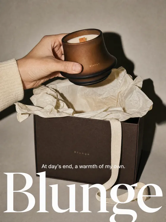 Campaign image of a brown candle of the same shape being lifted from a gift box with ribbon